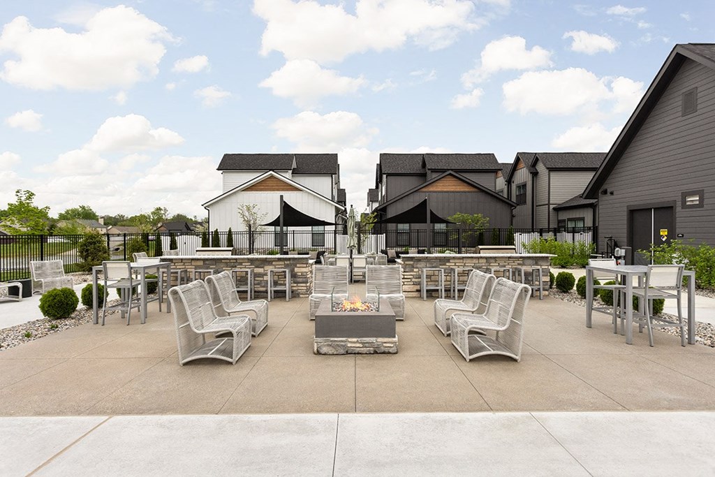 a patio with chairs and tables and a fire pit