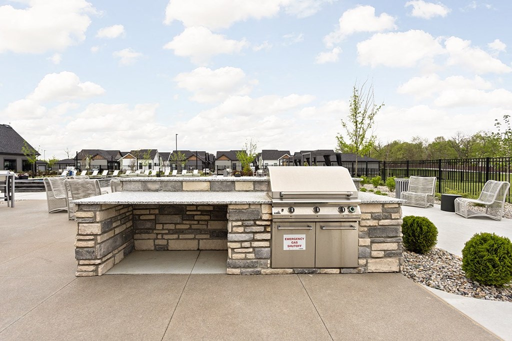 a stone outdoor kitchen with a grill and a patio