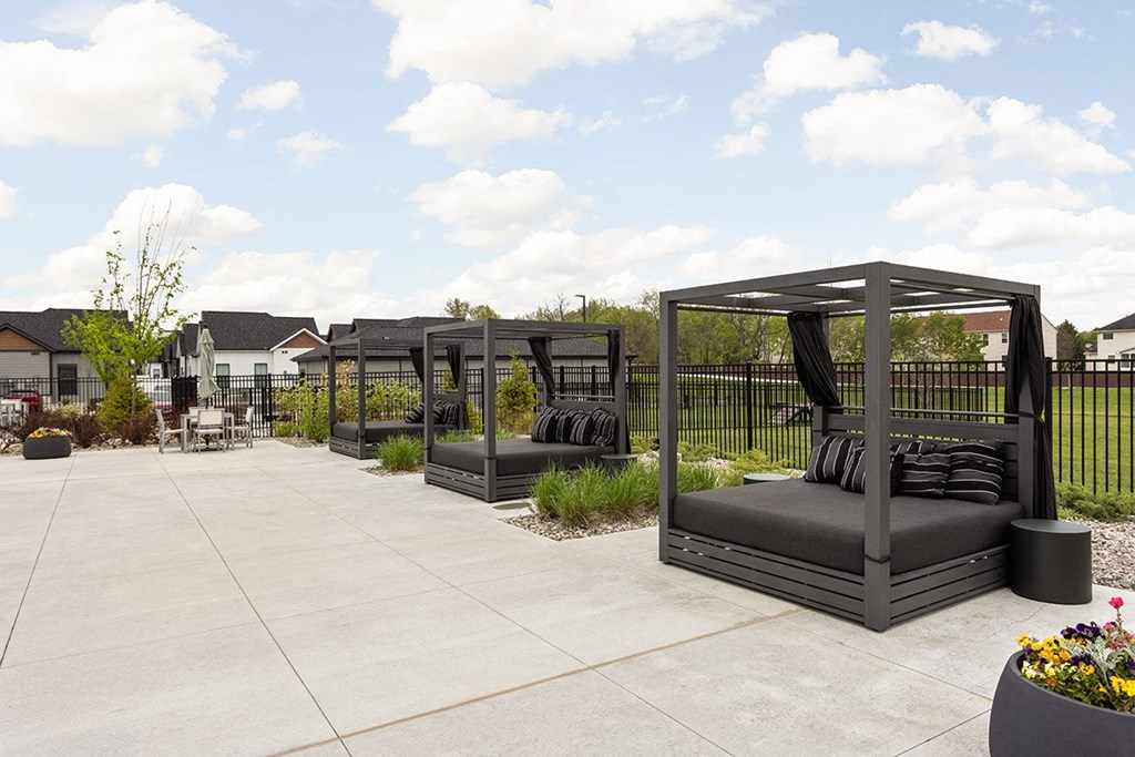 a patio with black couches and gazebos on it