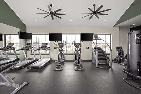 a gym with cardio equipment and windows in a building