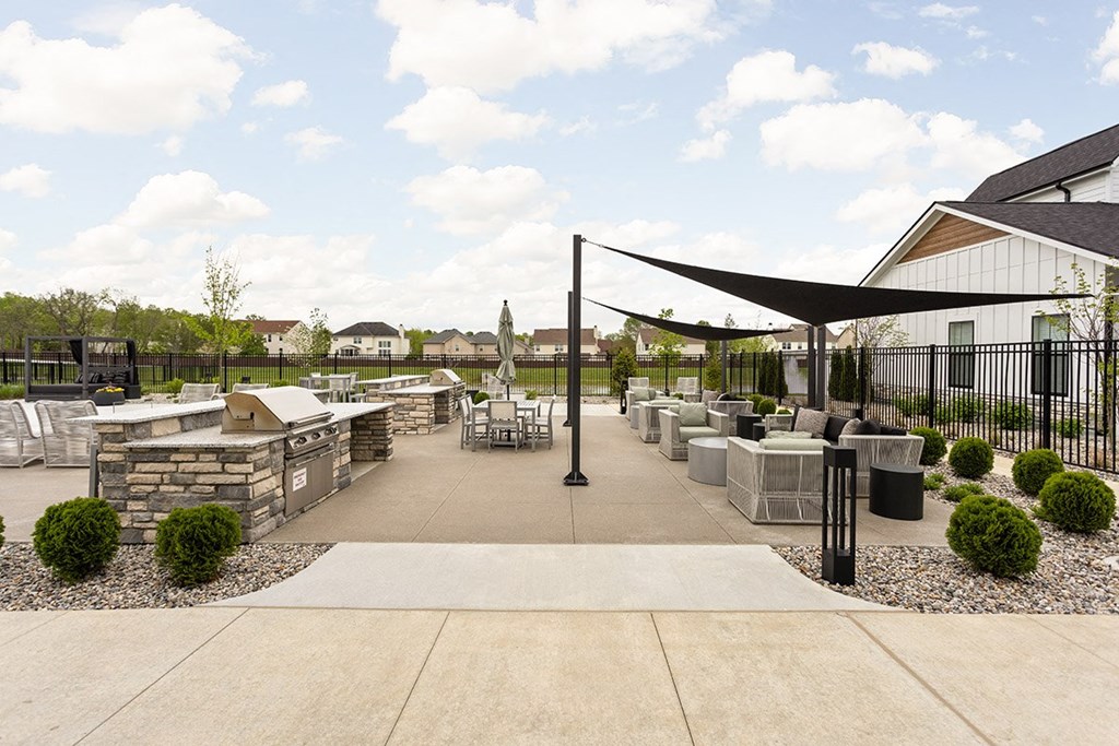an outdoor patio with tables and chairs and a black fence