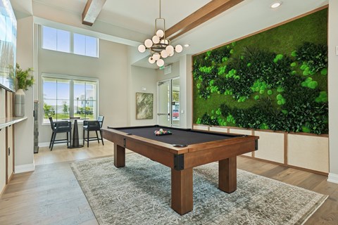 A pool table in a room with a green wall. at The Junction at Rockledge Apartments, Florida
