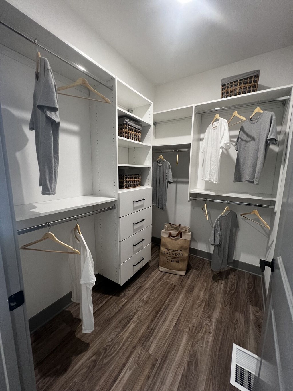 a walk in closet with white cabinets and wooden floors at Meridian at CityPlace, Woodbury