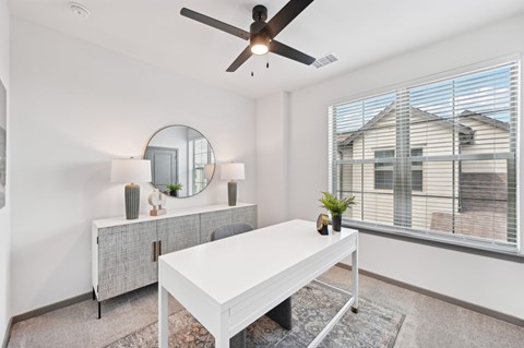 A white room with a table, a mirror, and a ceiling fan at The Hadley - North Port, FL Apartments, North Port, Florida