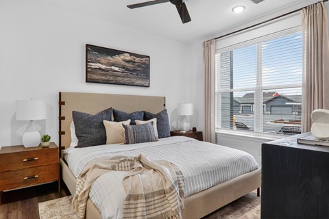 Modern bedroom with neutral decor and large window at The Logan Luxury Apartments, Nampa, Idaho