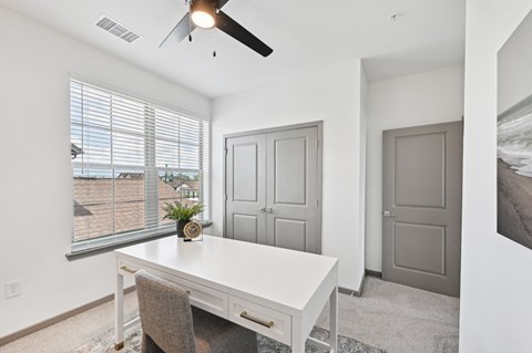 A room with a white desk and a ceiling fan. at The Hadley - North Port, FL Apartments, North Port