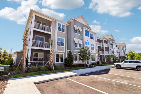 A row of modern apartment buildings with a car parked in the driveway.