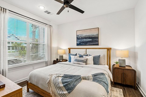 A bedroom with a bed, two lamps, and a painting on the wall.