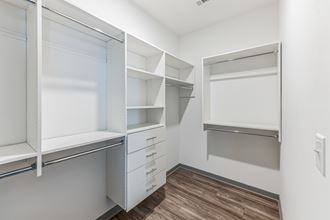 a walk in closet with white cabinets and drawers and