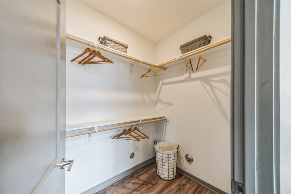 a walk in closet with shelves and a trash can in a room with a door at The BLVD at Wilson Crossings, Wyoming, MI 49418