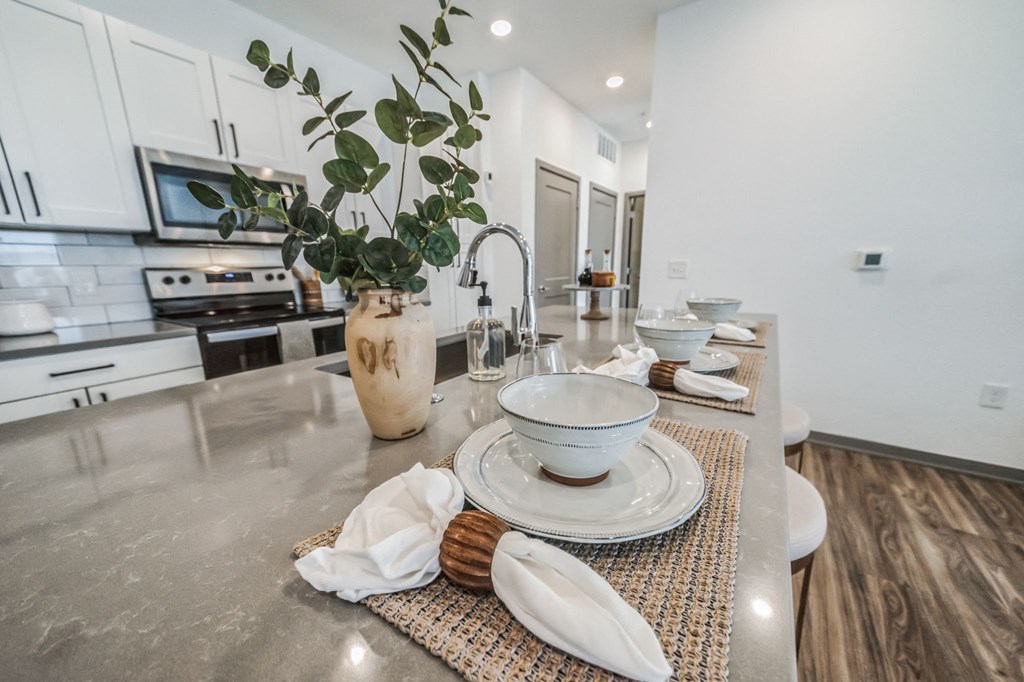 an open kitchen and dining area with white cabinets and stainless steel counter tops at The BLVD at Wilson Crossings, Wyoming Michigan