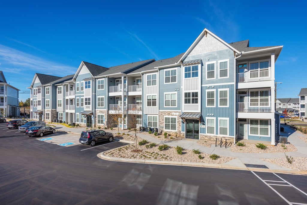 a large apartment building with cars parked in a parking lot  at Taylor Farms, Charlotte