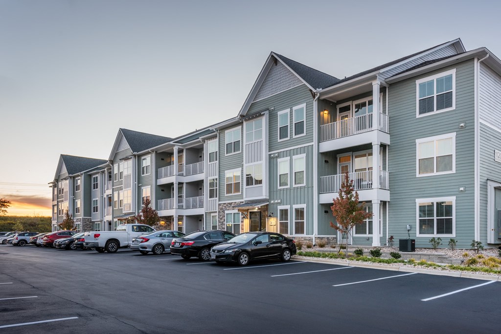 a row of apartment buildings with cars parked in front of them  at Taylor Farms, Charlotte