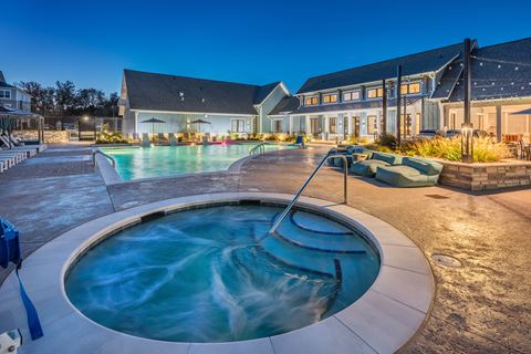 a swimming pool with a hot tub in front of a house