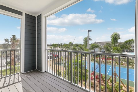 A balcony with a pool and palm trees in the background at The Junction at Rockledge Apartments, Rockledge, FL