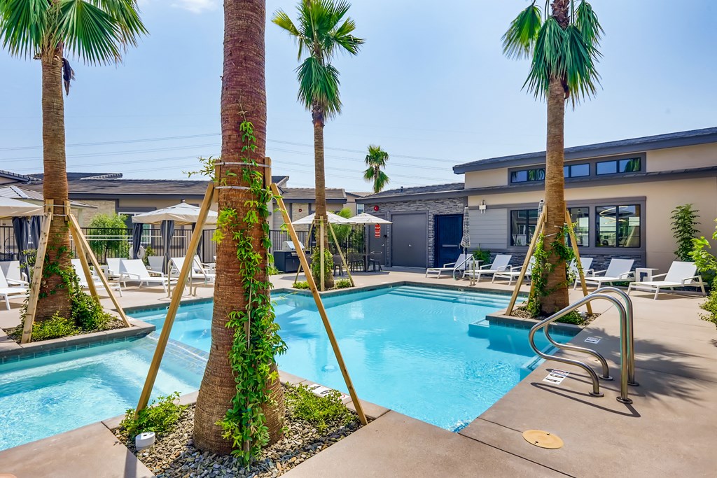 a swimming pool with palm trees and a building in the background at Grandstone at Sunrise, Peoria, Arizona