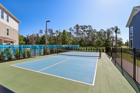 A tennis court with a blue surface and white lines, surrounded by a black fence.