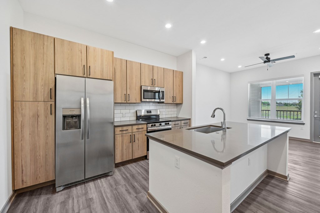 A modern kitchen with wooden cabinets and stainless steel appliances at The Concord Luxury Apartments, Florida