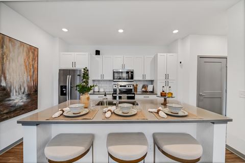 a kitchen with white cabinets and a island with four chairs