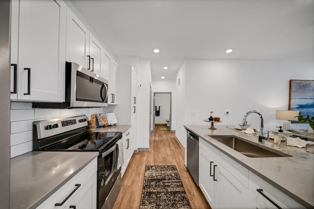 an open kitchen with stainless steel appliances and white cabinets at The BLVD at Wilson Crossings, Michigan