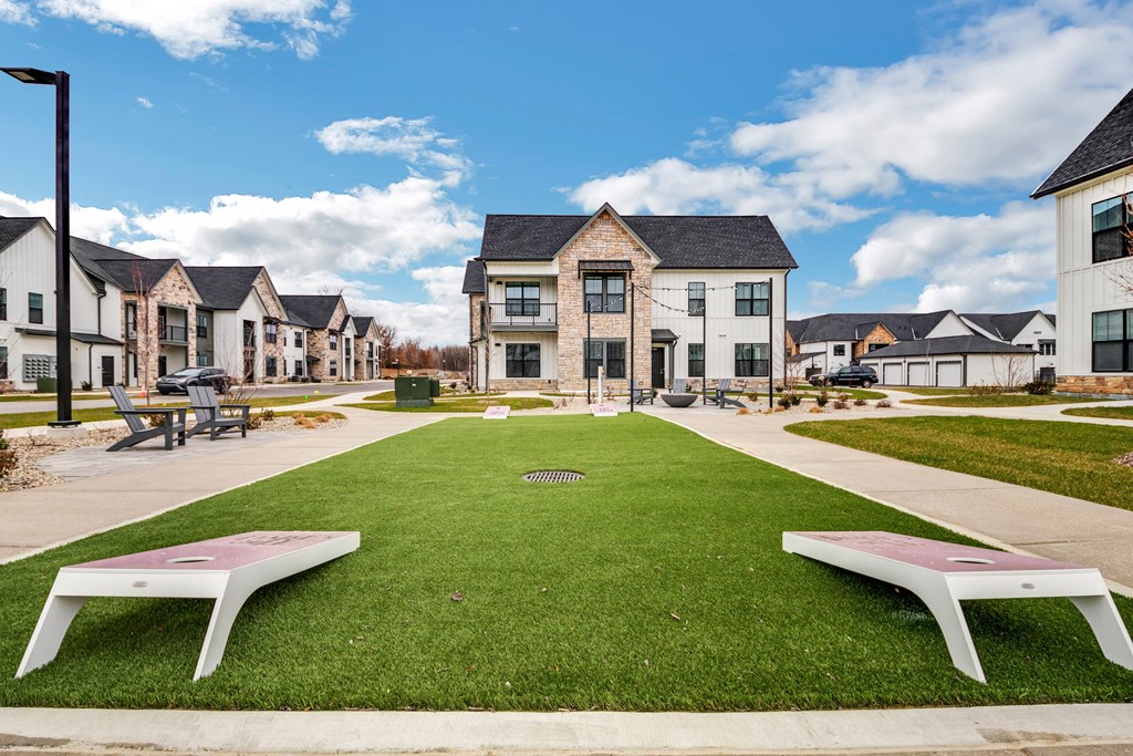 a green lawn with benches in front of houses at The BLVD at Wilson Crossings, Wyoming, 49418