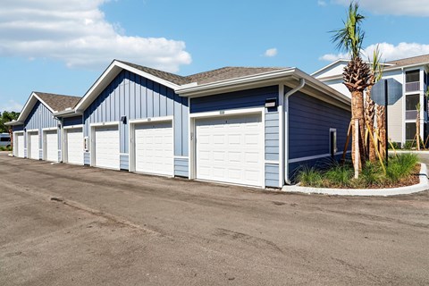 A row of blue and white garages with a palm tree in front.