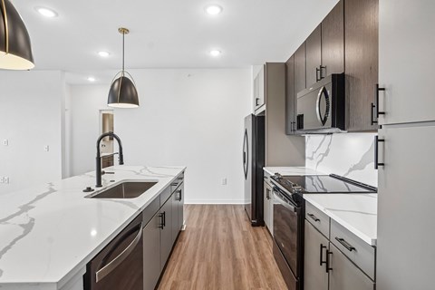 A modern kitchen with dark wood cabinets and white countertops.