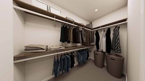 A walk in closet with clothes hanging and folded on shelves.