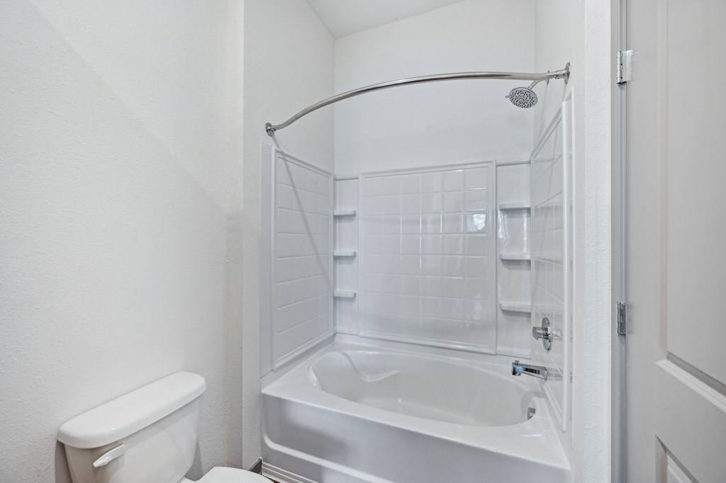 A white bathroom with a toilet, sink, and shower at The Concord Luxury Apartments, Sarasota 34240