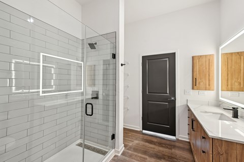A bathroom with a black door, a glass shower enclosure, and a white sink at The Hadley - North Port, FL Apartments, Florida, 34287