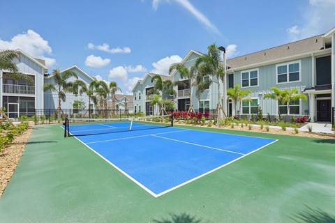 A tennis court is surrounded by apartment buildings at The Junction at Rockledge Apartments, Rockledge, FL, 32955