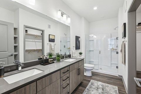 A modern bathroom with a double sink vanity and a walk-in shower. at The Junction at Rockledge Apartments, Florida