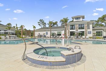 A hot tub sits in the middle of a pool surrounded by a tiled patio. at The Quinn Luxury Apartments, Florida