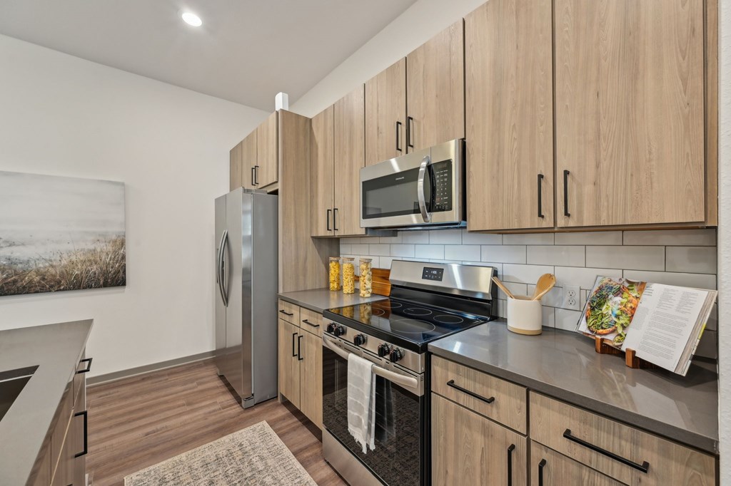 A kitchen with wooden cabinets and stainless steel appliances at The Concord Luxury Apartments, Sarasota 34240