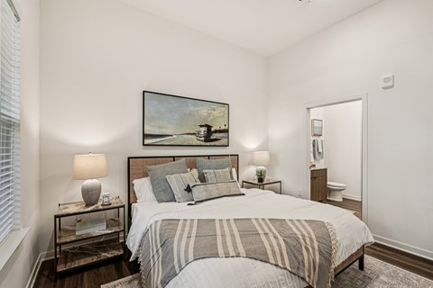 A bedroom with a large bed and a painting on the wall.