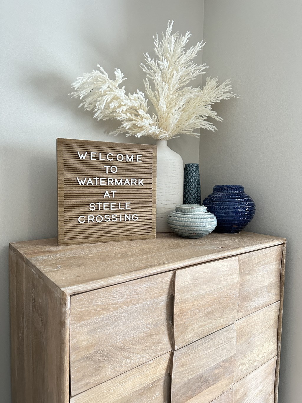 a wooden dresser with a vase and a sign on top of it at Watermark at Steele Crossing, Fayetteville, AR