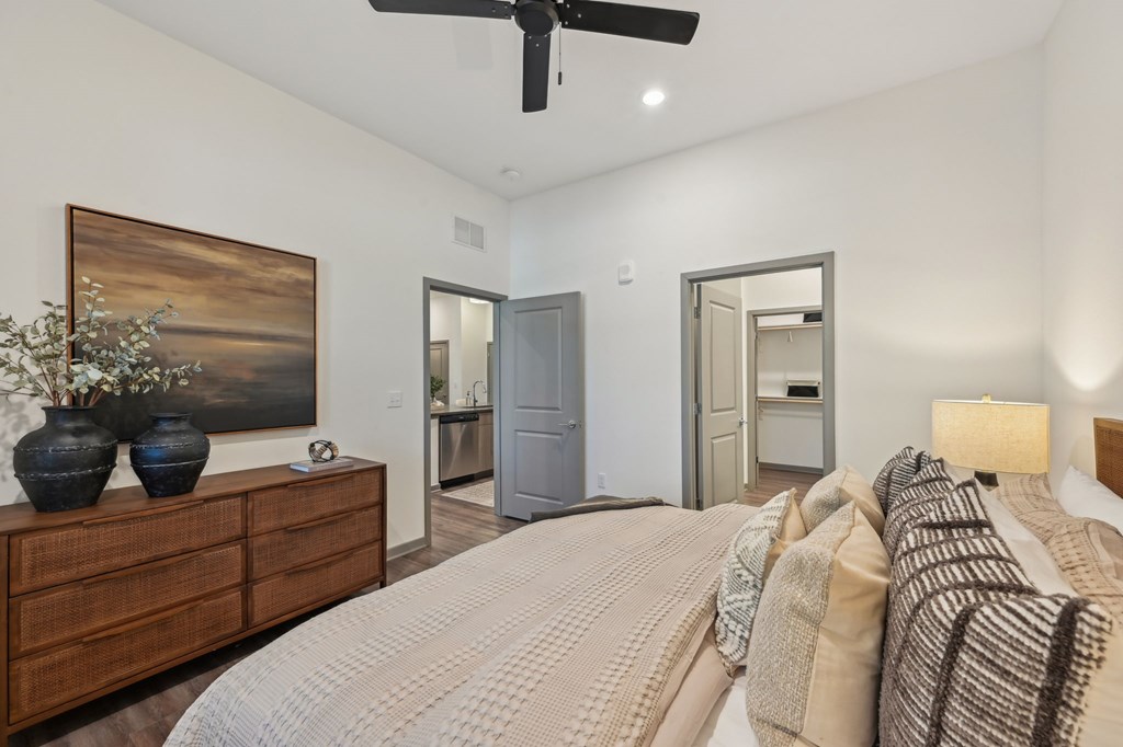 A bedroom with a bed, dresser, and ceiling fan at The Concord Luxury Apartments, Sarasota