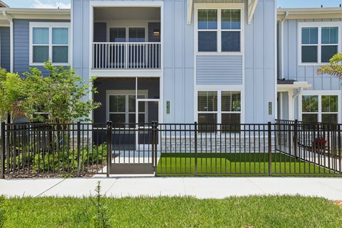 A blue building with a black fence and a green lawn in front at The Junction at Rockledge Apartments, Rockledge, Florida