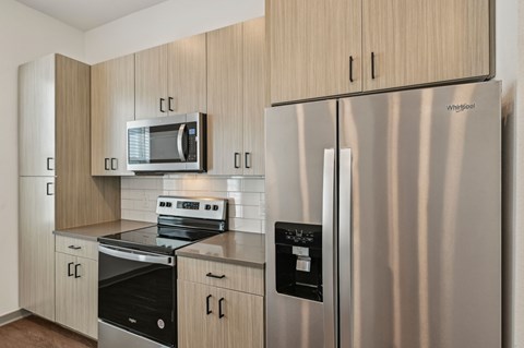 A modern kitchen with a stainless steel refrigerator and a microwave above the stove.
