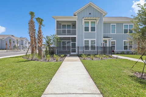 A modern two-story house with a balcony and a fence at The Junction at Rockledge Apartments, Rockledge, Florida