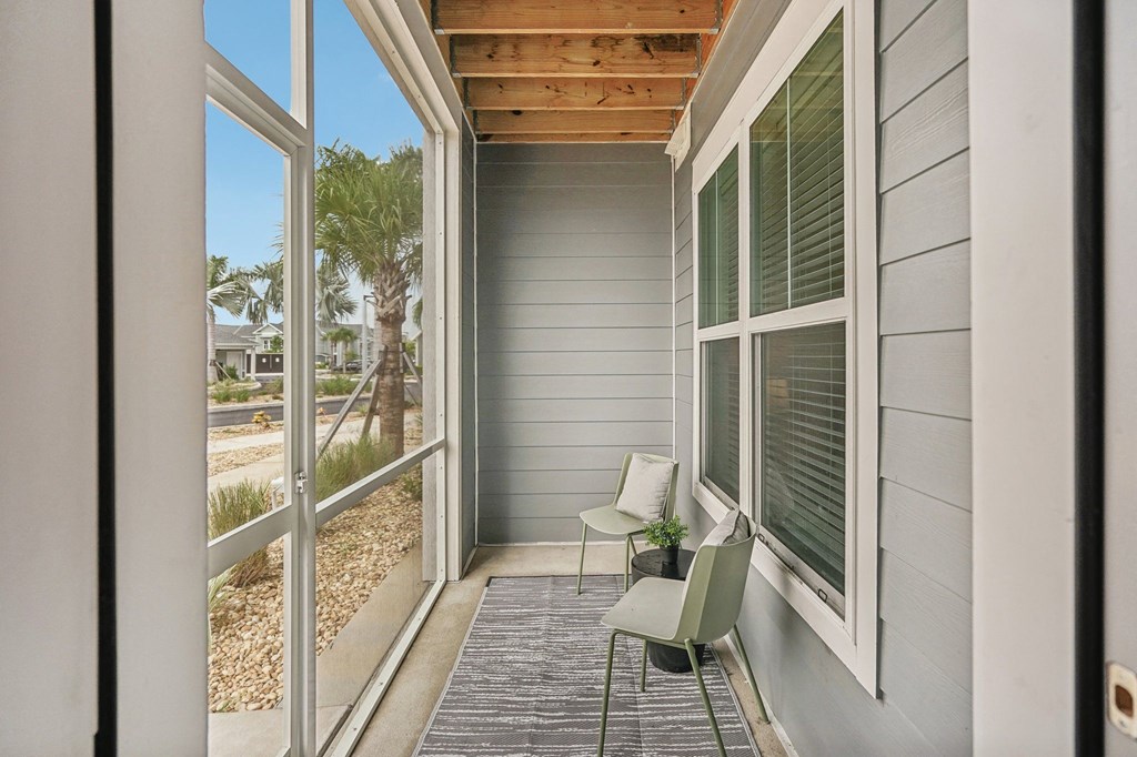 a covered porch with two chairs and sliding glass doors at Palm Grove in Ellenton, FL