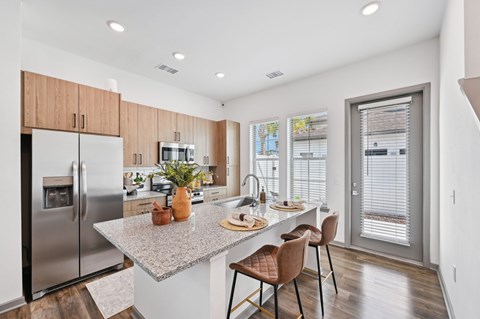 A kitchen with a refrigerator, sink, and a table with chairs. at The Hadley - North Port, FL Apartments, North Port