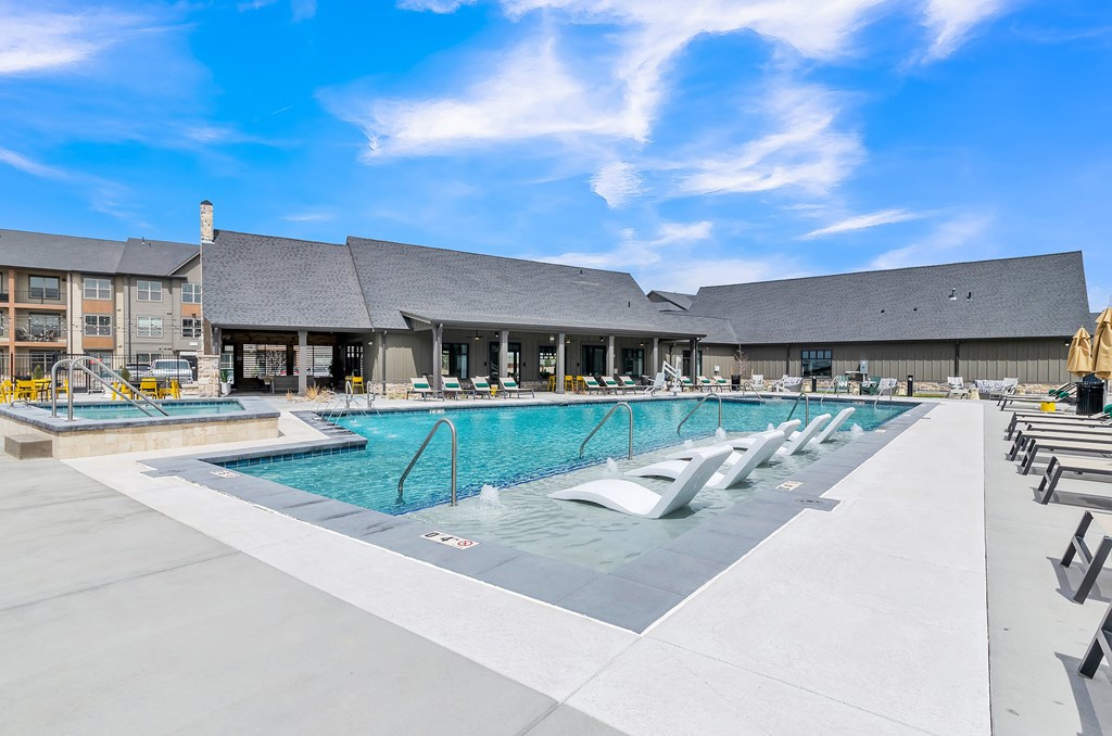 a swimming pool with lounge chairs and a building in the background at Apex, Colorado Springs, CO, 80923