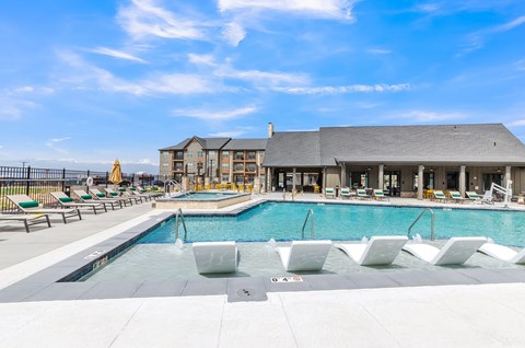 a large pool with lounge chairs and a building in the background at Apex, Colorado