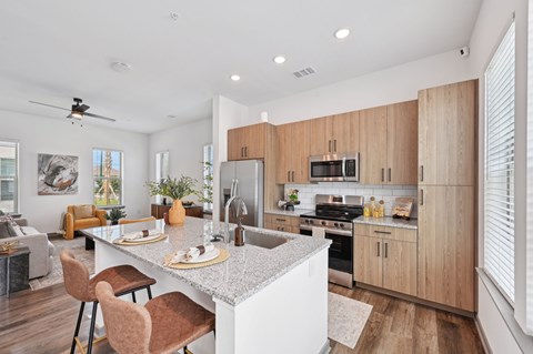 A modern kitchen with wooden cabinets and a white island at The Hadley - North Port, FL Apartments, North Port