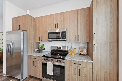 A kitchen with wooden cabinets and stainless steel appliances. at The Hadley - North Port, FL Apartments, North Port, Florida