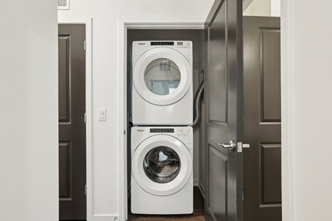 A white front load washing machine is in a small laundry room at The Junction at Rockledge Apartments, Rockledge 32955