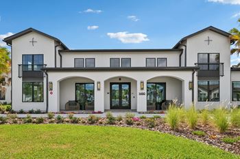 A white two-story house with a balcony on the second floor. at The Hadley - North Port, FL Apartments, North Port
