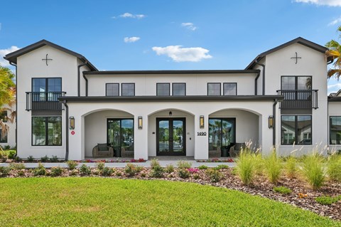 A white two-story house with a balcony on the second floor. at The Hadley - North Port, FL Apartments, North Port, FL, 34287