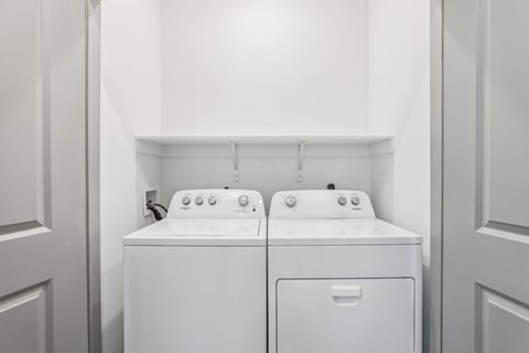 Two white front loading washing machines in a laundry room at The Junction at Rockledge Apartments, Rockledge, FL, 32955